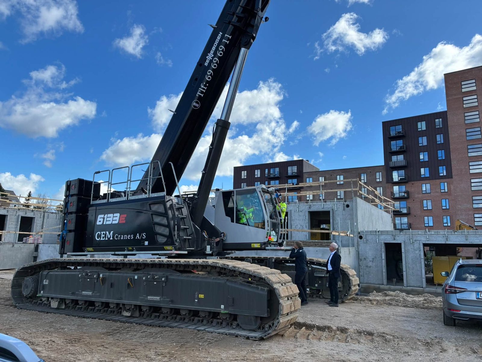 Sennebogen 6133E bæltekran med CEM Cranes-logo ved et boligbyggeri